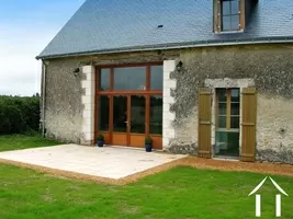 The gîte is a classic barn conversion. Built in the local imestone (tuffeau) it has an ardoise slate roof, oak dormer (lucarne) windows and double glazing.   The interior of the gîte is dominated by a spectacular vaulted ceiling with exposed oak beams and a large mezzanine balcony.   It has its own private aspect, facing away from the Main House and overlooks open countryside.  This picture shows the entrance with dining terrace and the downstairs bedroom window.